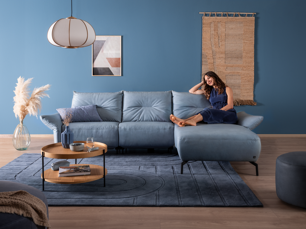 2xl-SALVIA (1) Frau lehnt entspannt auf dem blauen Sofa SALVIA mit Chaiselongue
