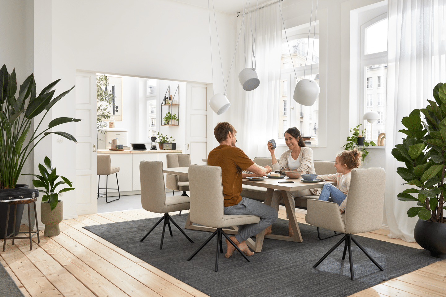 Familie sitzt im Esszimmer bei Tisch und frühstückt