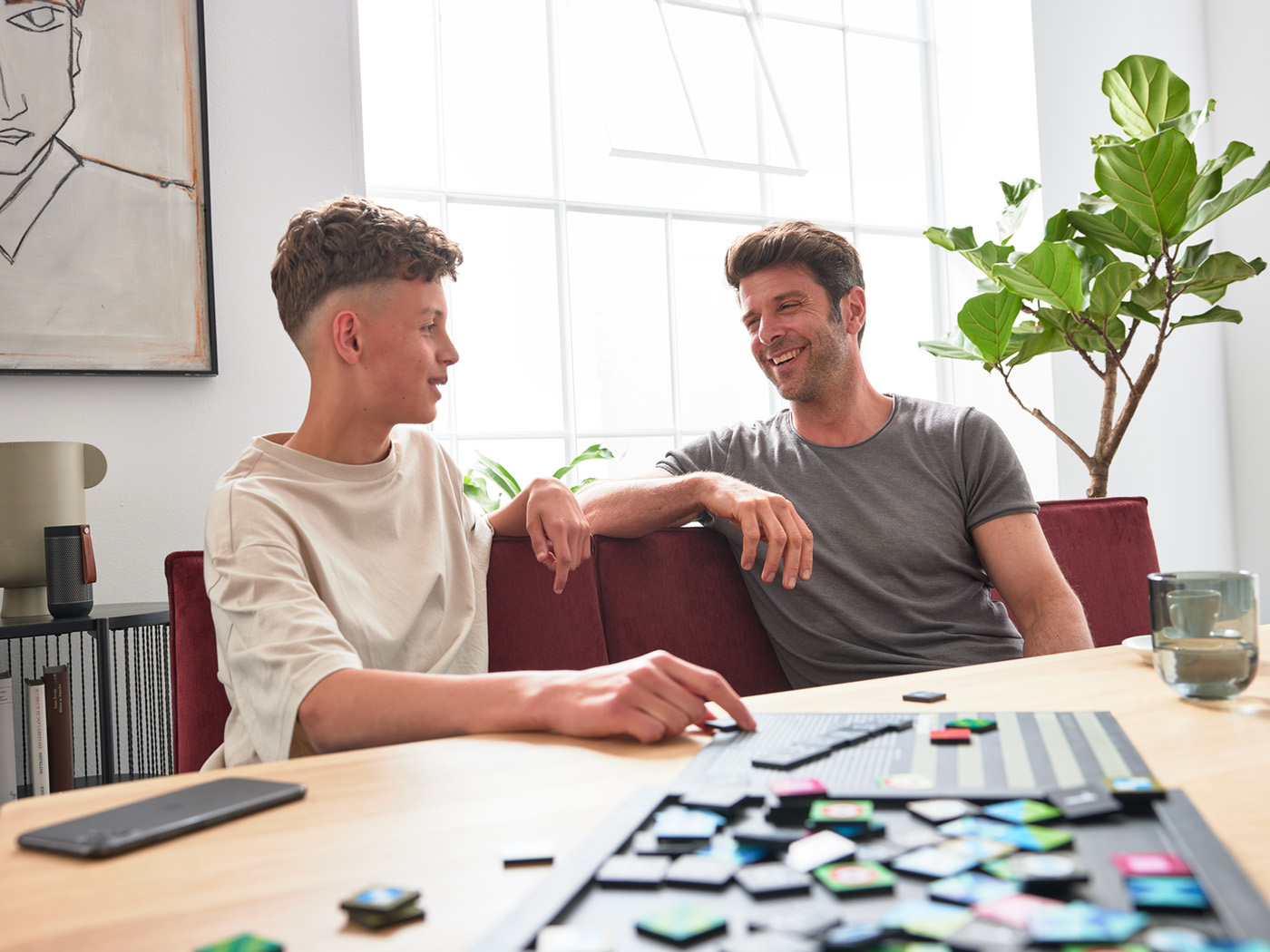 Vater und Sohn spielen am Esstische und sitzen auf der Esszimmerbank Dulcis