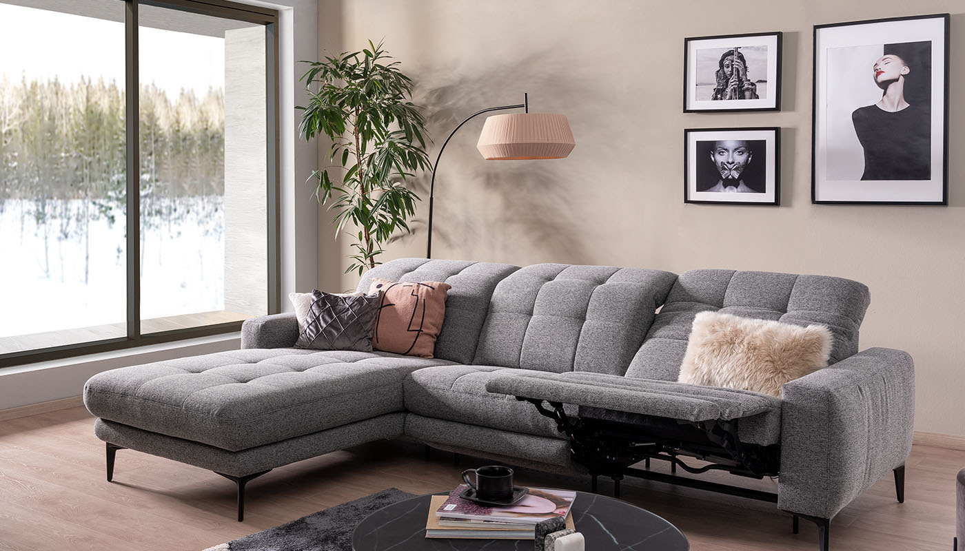 ada mindful living – Relaxfunktion Sofa almere Graues Sofa in einem schlichten Wohnzimmer mit Winterlandschaft vor dem Fenster
