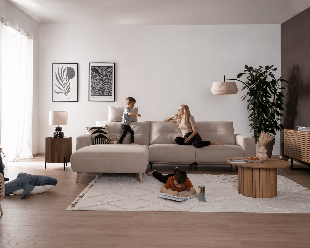 Frau spielt mit 2 Kindern auf dem Sofa Alika