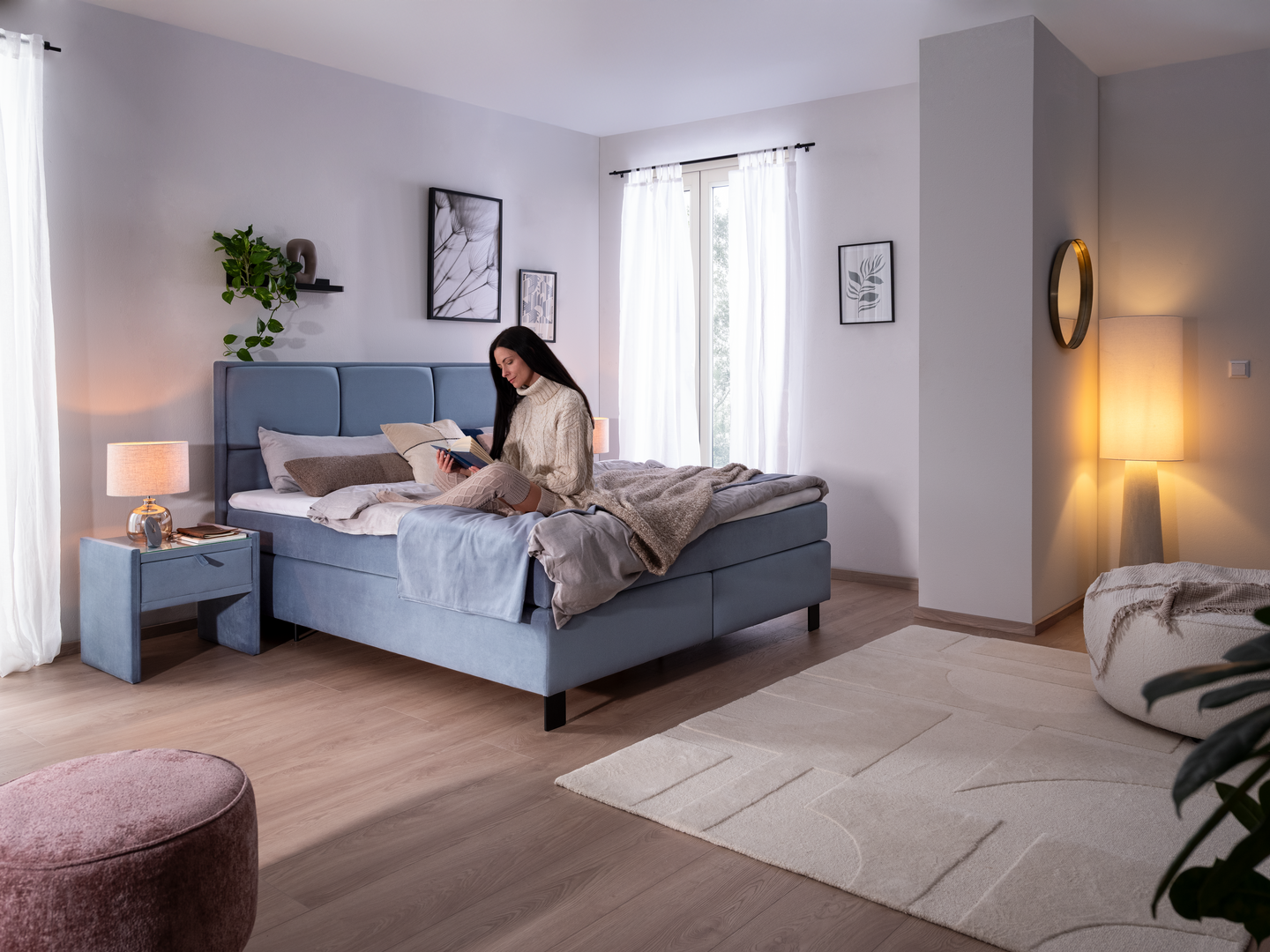 3xl-SIDUS (6) Frau sitzt auf dem hellblauen Boxspringbett Sidus und liest ein Buch