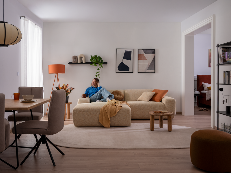 xl-PINEA beiges ADA Sofa PINEA mit Model in einer kleinen Wohnung
