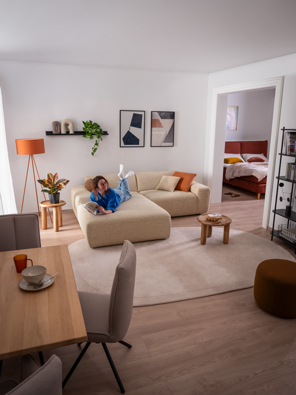 Frau liegt am Bauch am Sofa Pinea in hellem, freundlichen Wohn- Esszimmer